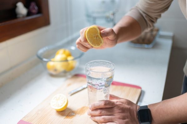 Homem espreme limão em copo de água com limão - Metrópoles