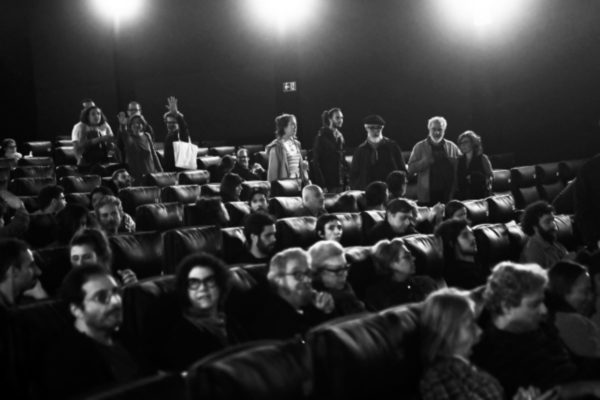 Fotografia em preto e branco mostra pessoas no cinema 