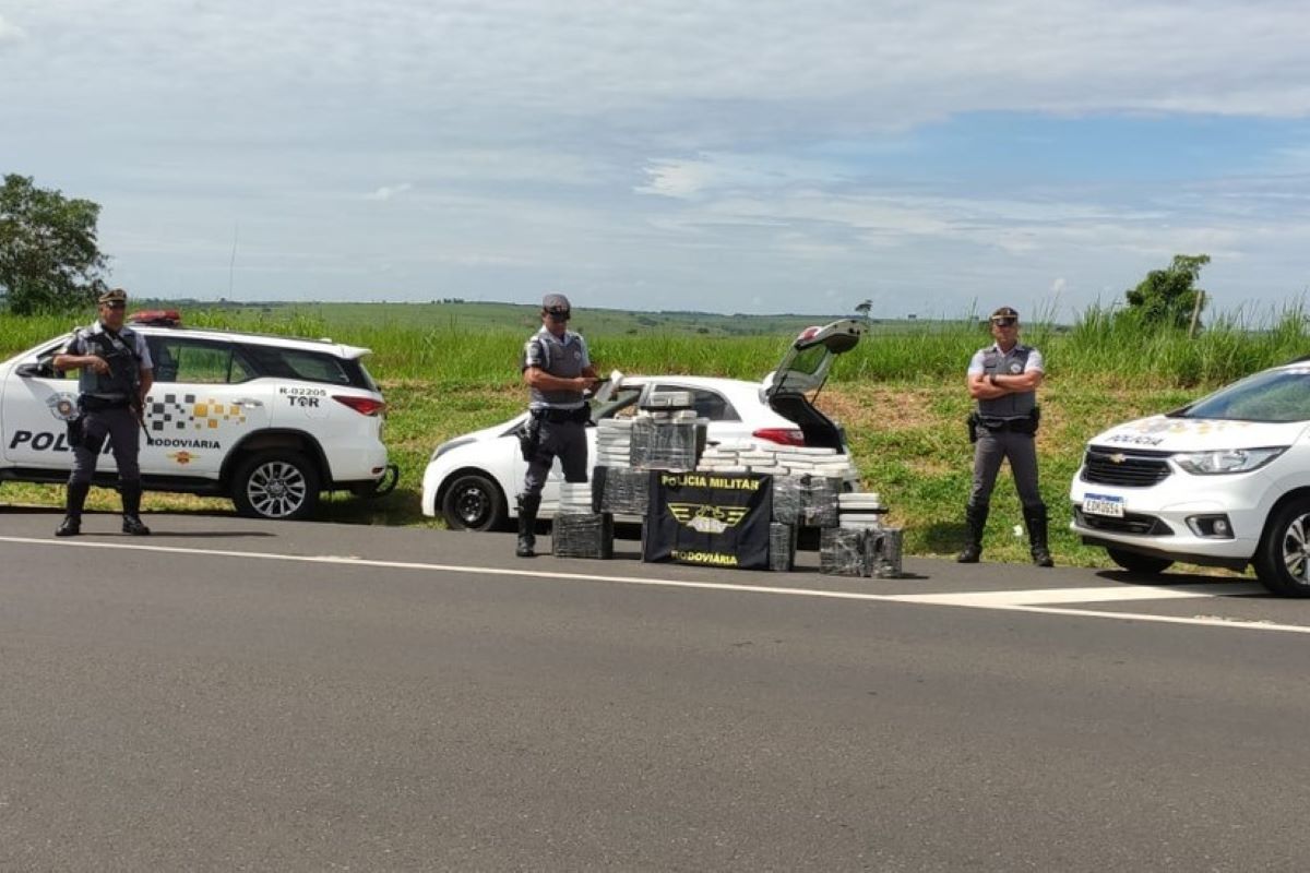 Imagem colorida mostra policiais retirando tijolos de maconha de dentro de carro no interior de São Paulo; motorista foi preso - Metrópoles