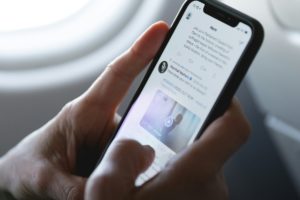 Fotografia colorida mostrando mão mexendo em celular dentro de avião-Metrópoles