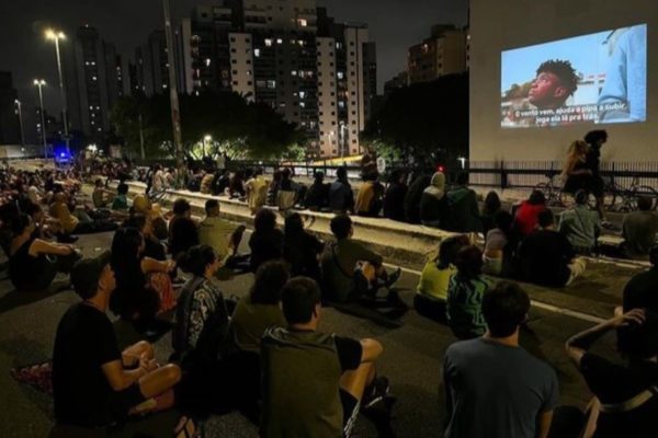 Pessoas assistem filme projetado em parede de prédio em São Paulo 