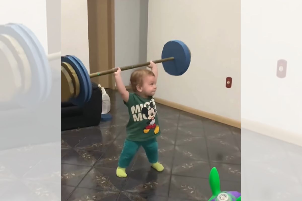 Foto colorida de um bebê levantando peso - Metrópoles