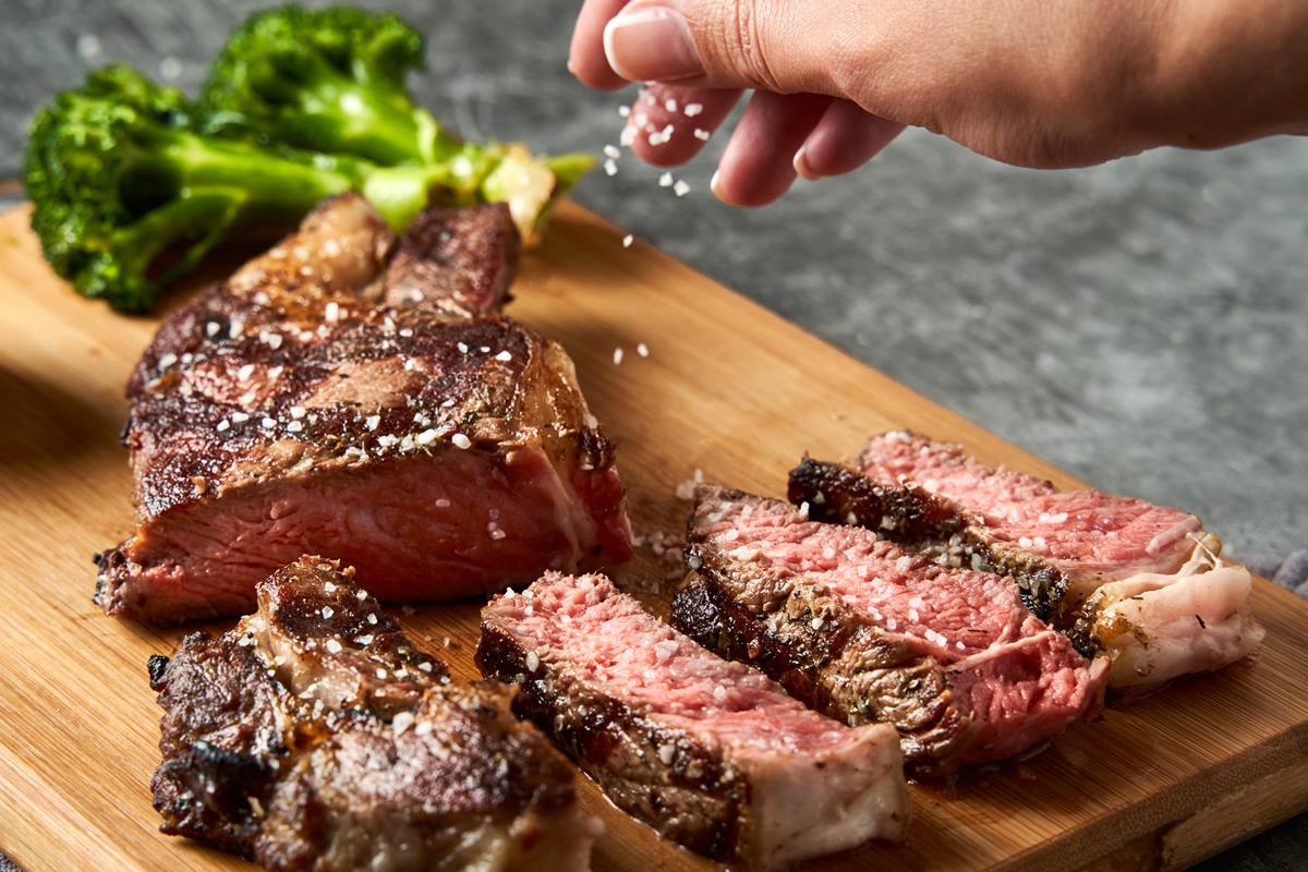 Foto colorida de m&atilde;o colocando sal grosso em churrasco - Metr&oacute;poles