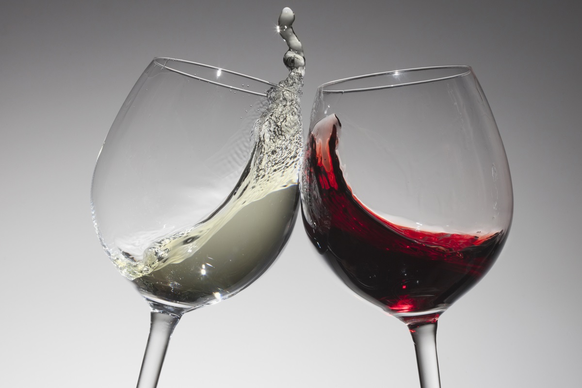 Foto colorida de duas taças de vinho, sendo uma de vinho branco e outra com tinto - Metrópoles