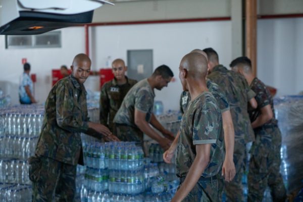 Fotografia colorida mostrando militares carregando garrafas de água-Metrópoles