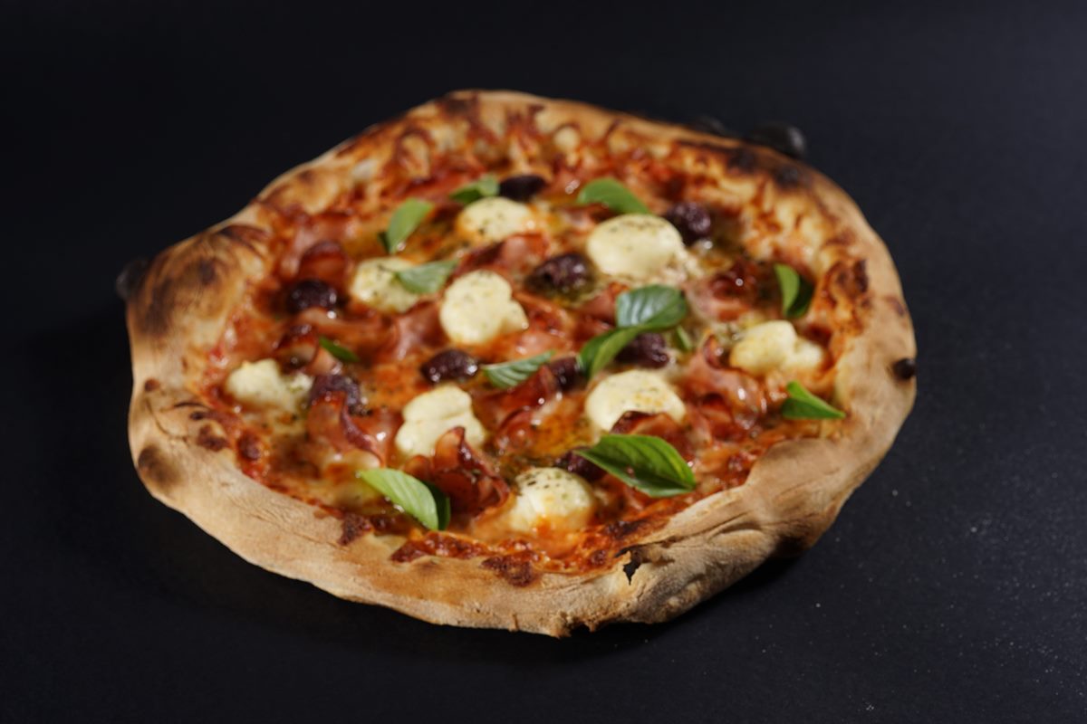 Na foto colorida, uma pizza recheada com queijo e vários toppings - Metrópoles 