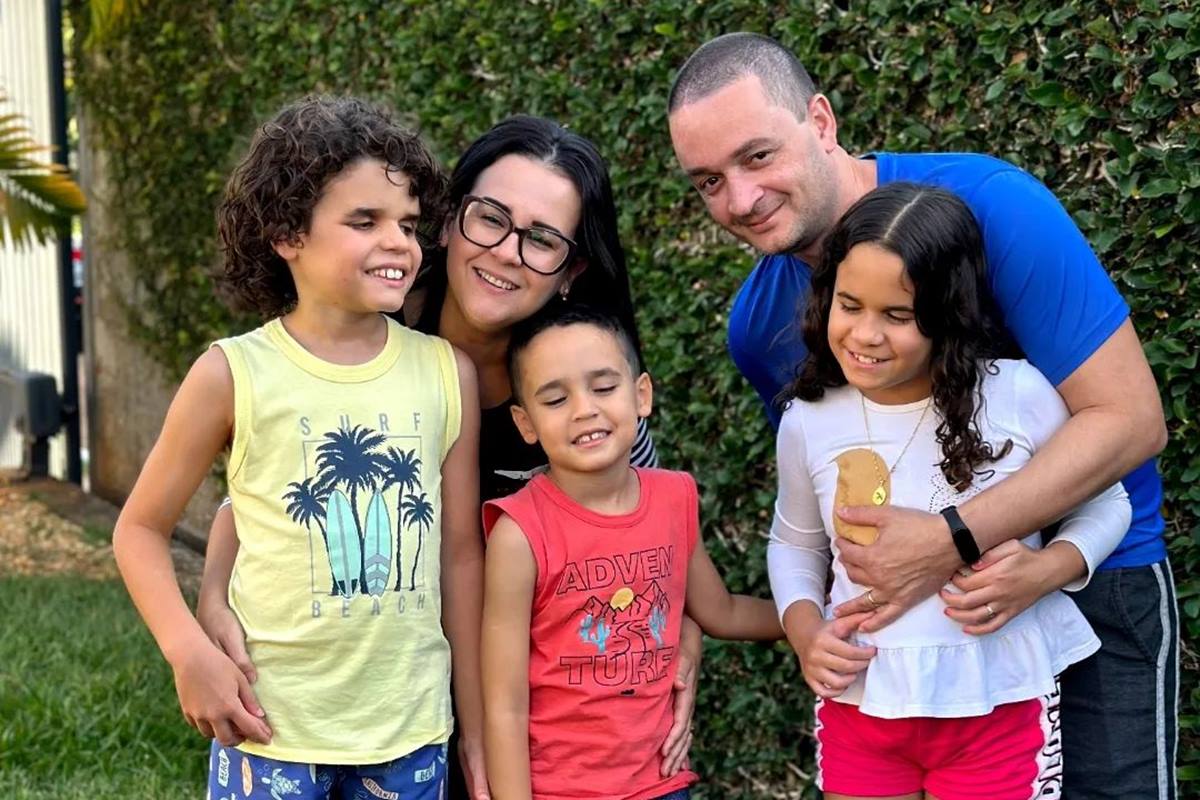 Foto colorida de mulher e homem com dois meninos e uma menina. Eles estão em um jardim - Metrópoles